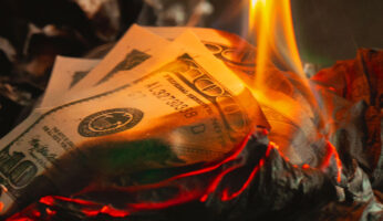 Dollar bill being set on fire by a small candle